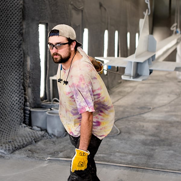 paint shop worker moving beams through the paint booth